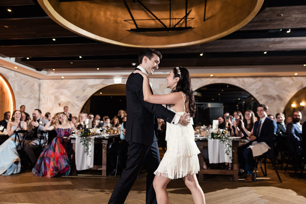 Bride and groom dance at their Chicago Winery wedding reception as guests watch and smile