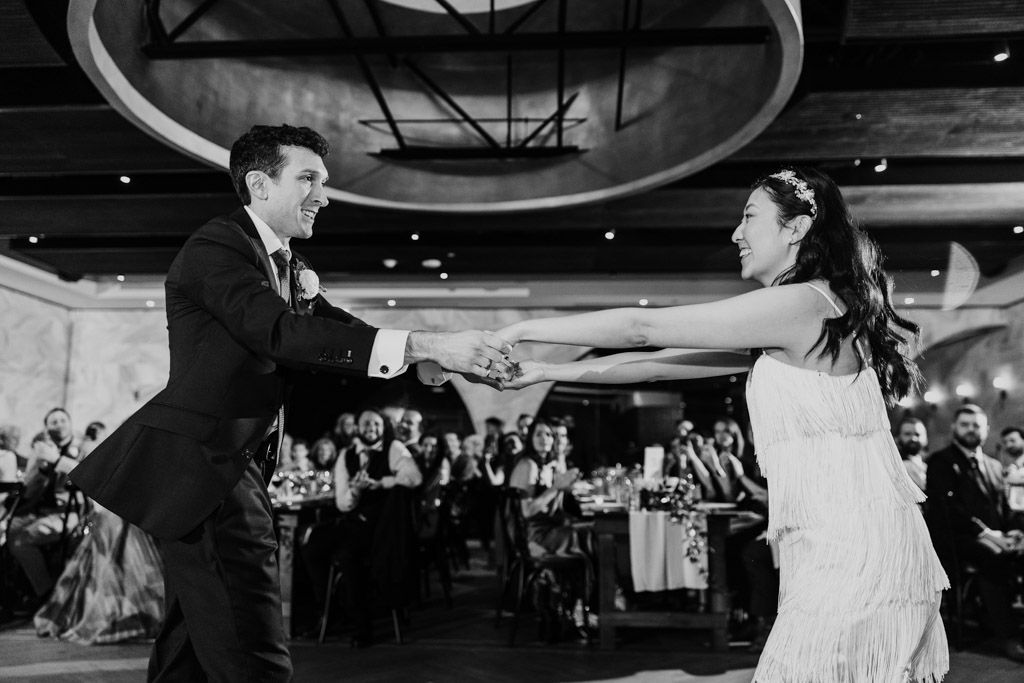 Black and white phot of bride and groom couple dancing together at their Chicago Winery wedding reception, surrounded by seated guests