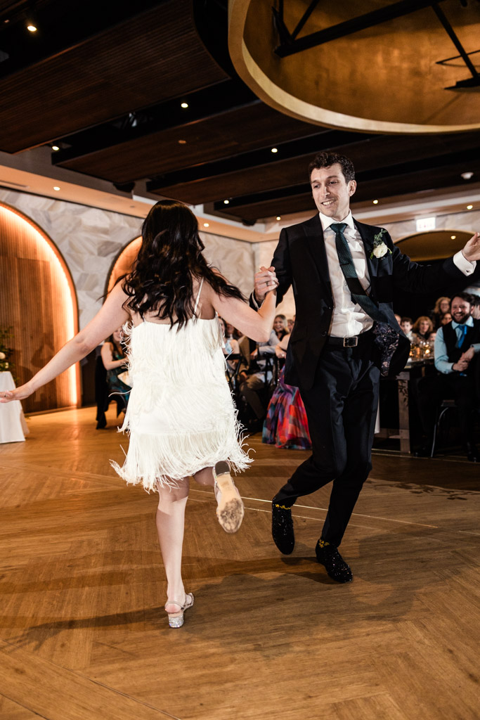 Newlyweds in formal attire joyfully dancing together on a wooden floor at Chicago Winery wedding reception