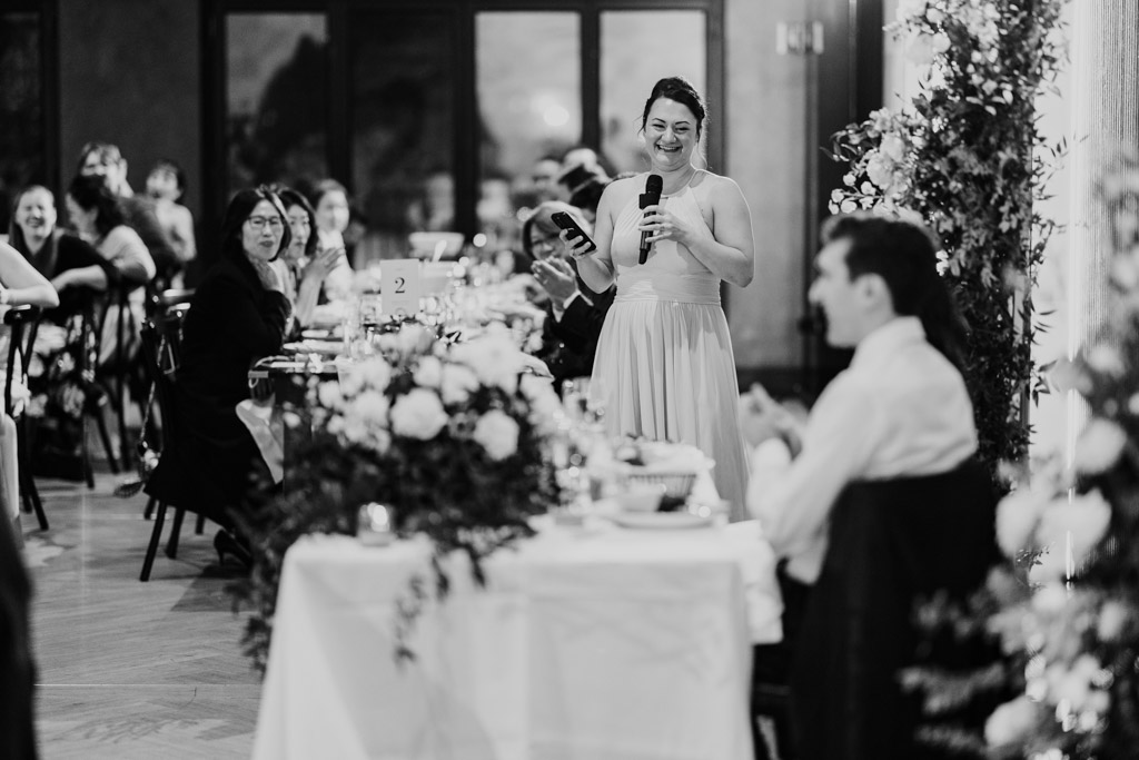 Black and white photo of Maid of Honor giving a speech with a microphone at Chicago Winery wedding reception