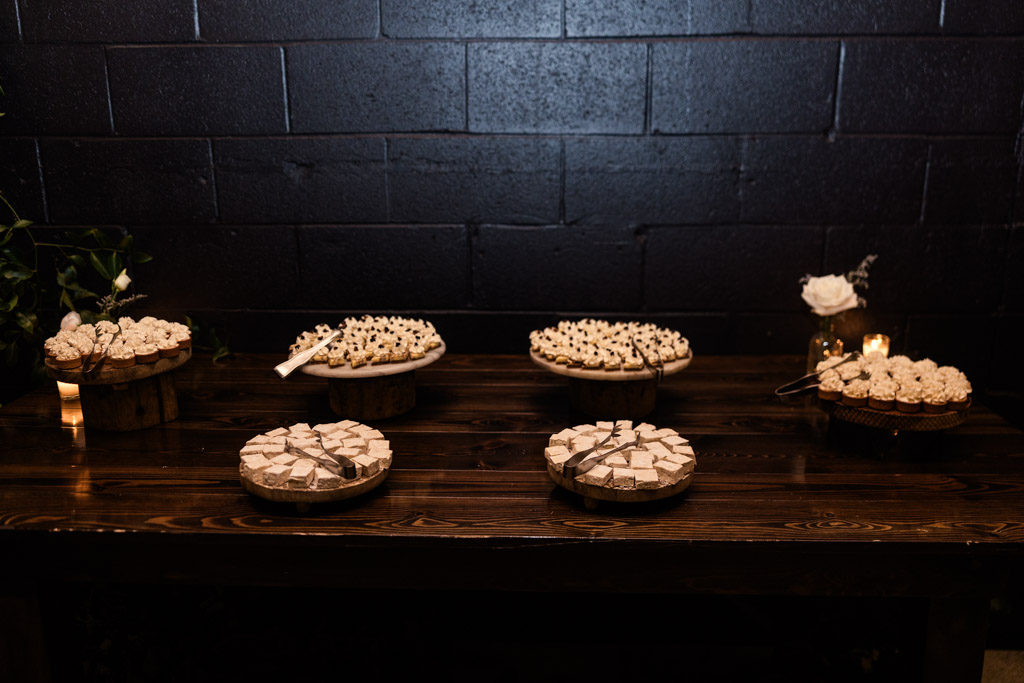 A dark wooden table with assorted bite-sized desserts on rustic stands for Chicago Winery wedding reception