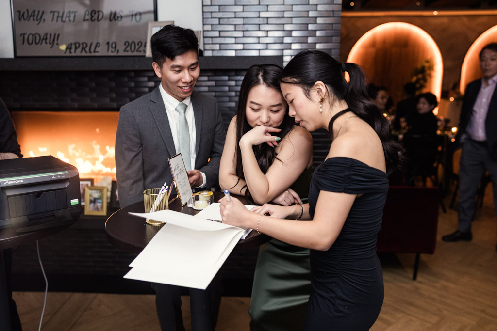 Guests add their photo and message to the guestbook on a round table at Chicago Winery wedding reception