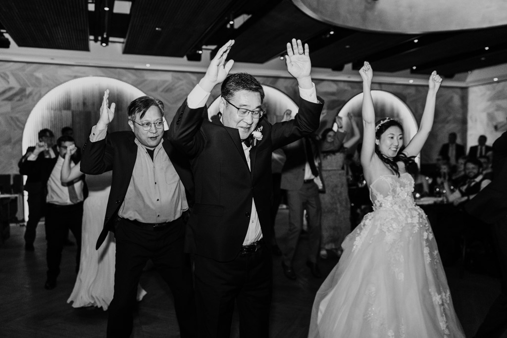 Black adn white photo of bride, her father, and other guests performing a choreographed dance during Chicago Winery wedding reception