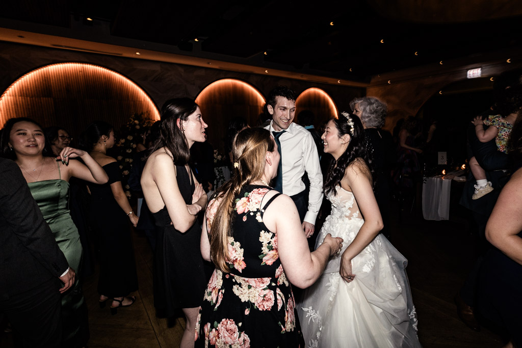 Bride and groom laugh and talk with guests on the dance floor at a Chicago Winery wedding reception