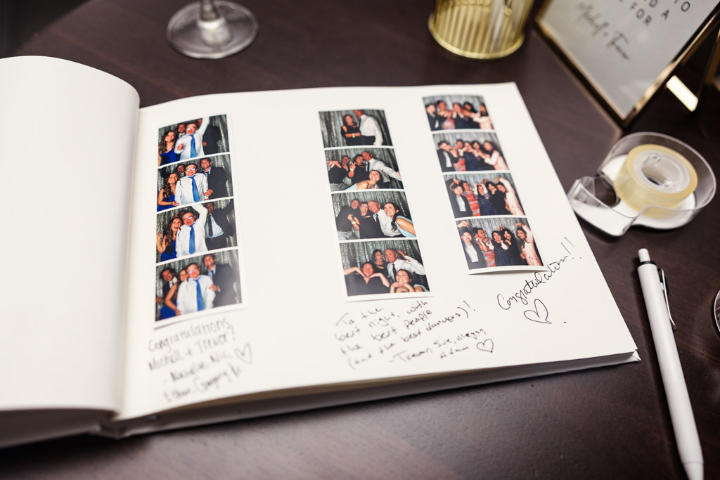 An open guestbook with photo booth strips and handwritten messages sits on a dark table during Chicago Winery weddng reception, with a pen and tape nearby