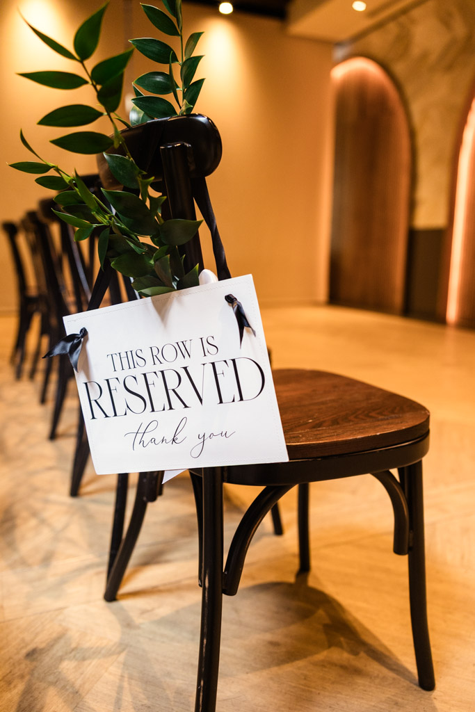 A black chair with reserved sign and greenery tied to the backrest for Chicago Winery wedding ceremony