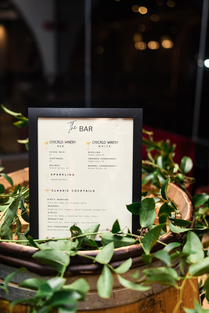 Framed bar menu on a wooden barrel at Chicago Winery, decorated with green vines and listing wines and classic cocktails