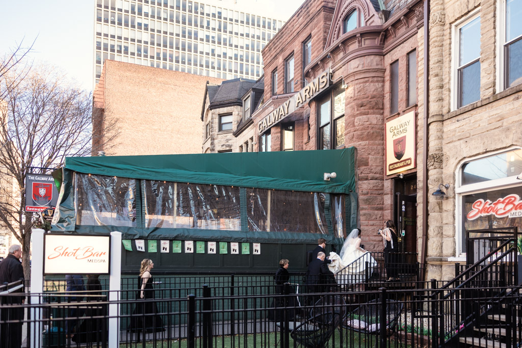 Bride, groom and guests enter Galway Arms pub during their spring Chicago wedding celebration