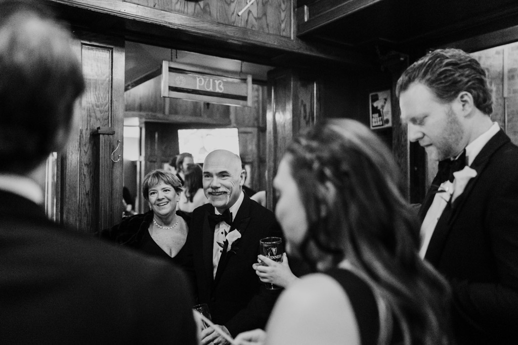 Black and white photo of guests smiling and talking together inside Galway Arms in Chicago
