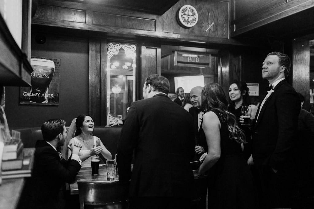 Black and white photo of guests smiling and talking with the newlyweds in a booth at Galway Arms