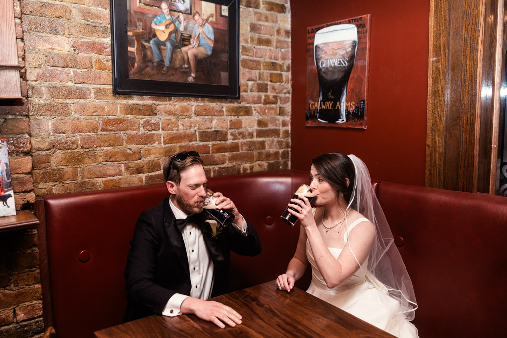 Bride and groom in wedding attire drink pints of stout together at Galway Arms Restaurant and Pub
