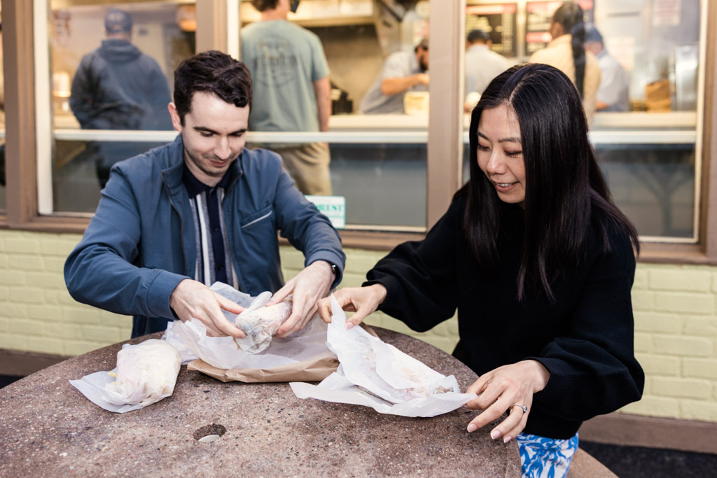 Engaged couple sits at a table outside Johnnie's Beef in Oak Park, unwrapping their food together