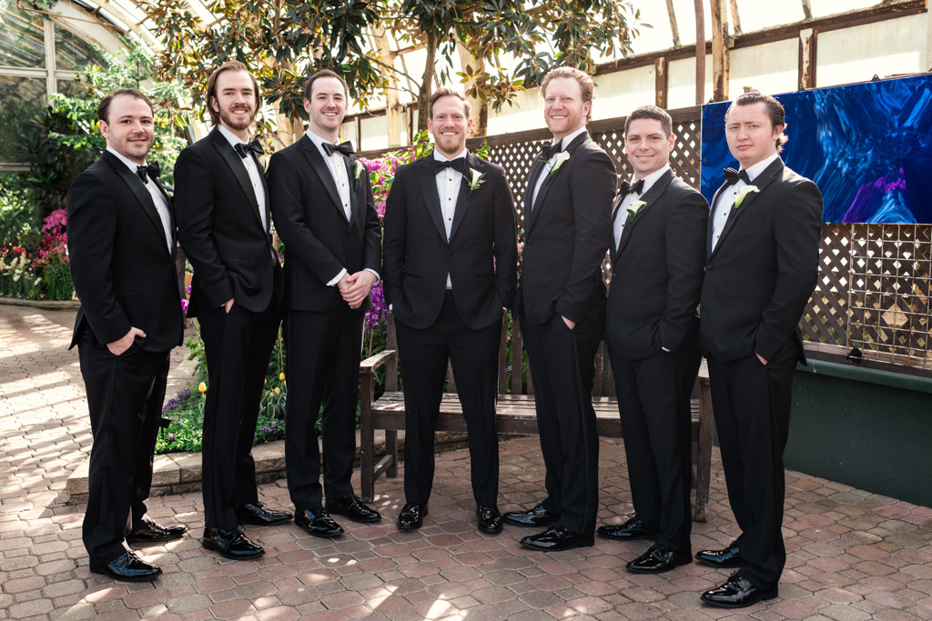 Portrait of groom and groomsmen in black tuxedos inside Lincoln Park Conservatory in Chicago