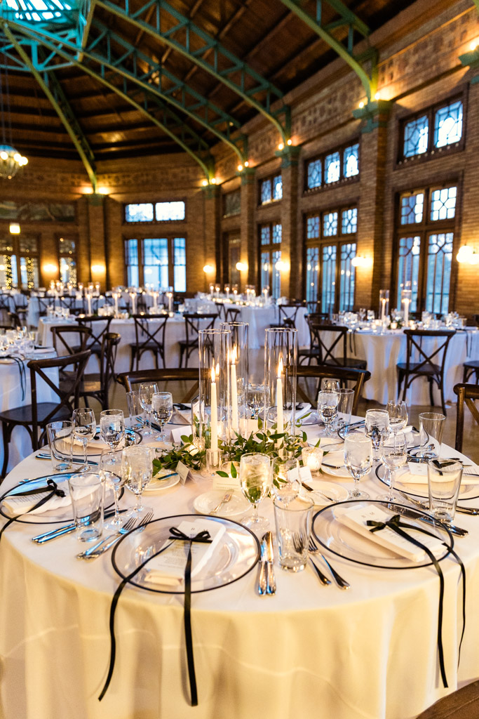 Wedding reception space at Cafe Brauer with round tables, white linens, sparkling glassware, and tall candle centerpieces