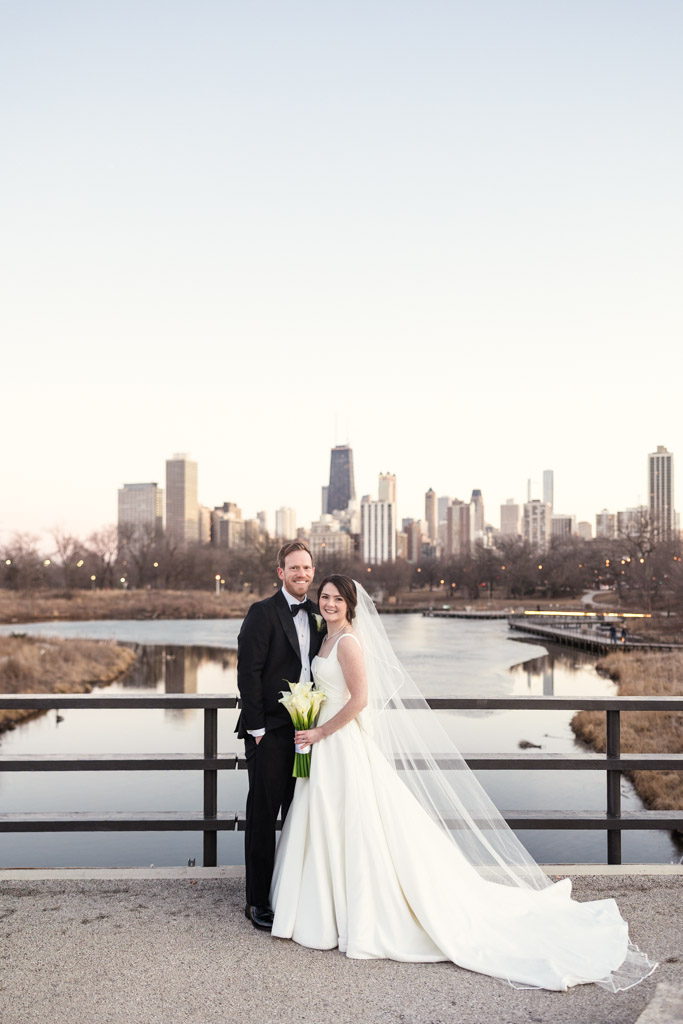 Portrait of bride and groom on a bridge near Cafe Brauer, with Chicago skyline in the background at sunset
