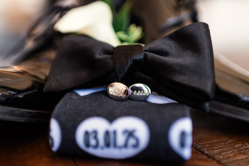 Detail photo of black bow tie, cufflinks, and socks with wedding date in white hearts for spring Chicago wedding celebration