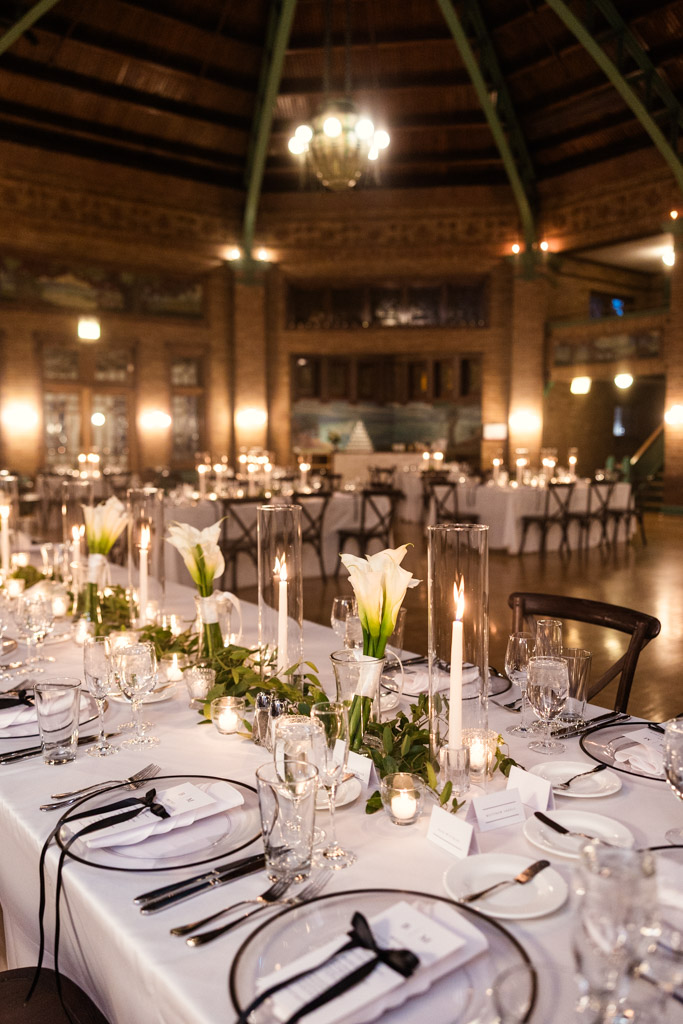 Wedding reception space at Cafe Brauer with white table settings, candles, calla lilies, and soft ambient lighting