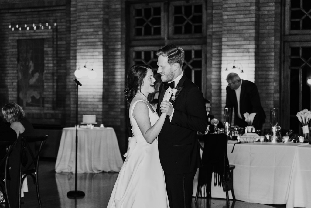 Black and white photo of bride and groom during their first dance inside Cafe Brauer