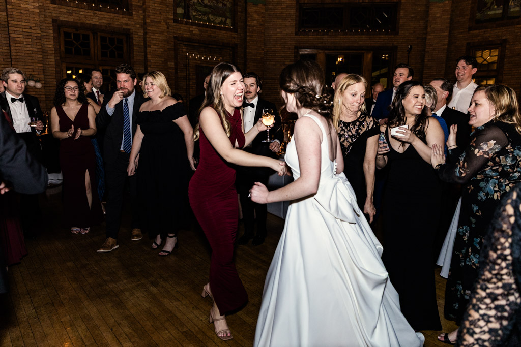 Bride in a white dress dances with guests during her wedding reception at Cafe Brauer
