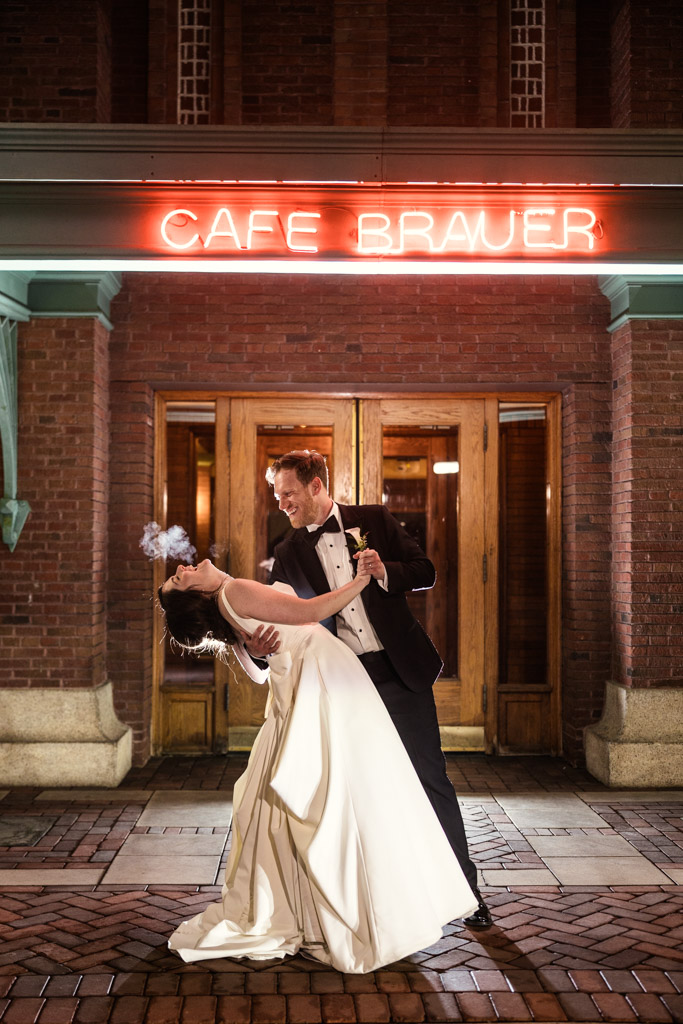 Groom dips his bride in a white dress under the glowing neon