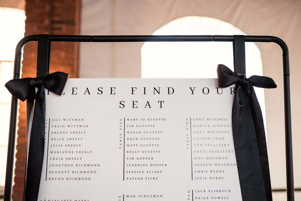 Wedding seating chart for Cafe Brauer reception, featuring black ribbons on the corners and guest names listed in columns