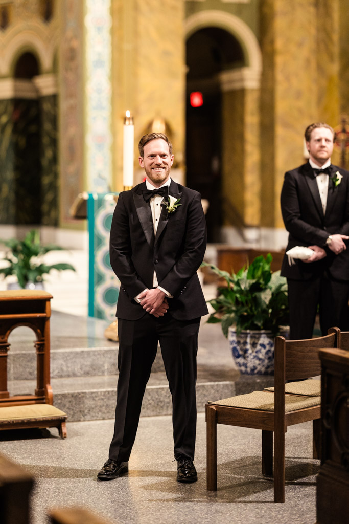 Groom smiles while watching the bride walk down the aisle inside St. Clement Church in Chicago
