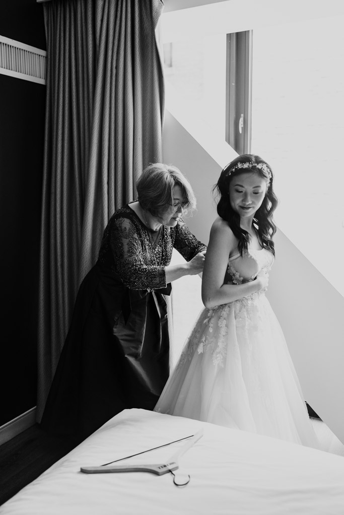 Bride's mother helps bride adjust her dress near a window at The Godfrey Hotel in downtown Chicago