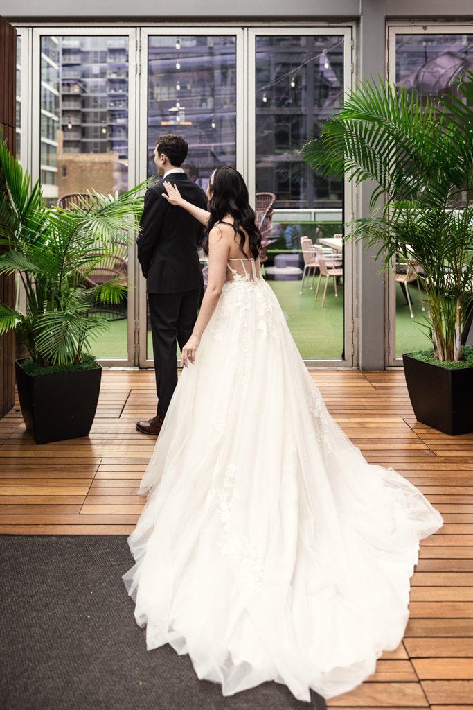 Bride in a white gown taps groom on the shoulder during their first look The Godfrey Hotel in downtown Chicago