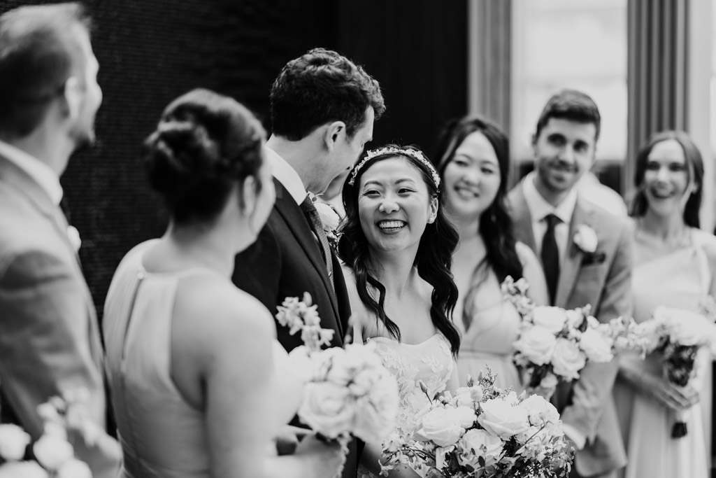 Candid black and white photo of happy bride and groom at The Godfrey Hotel in downtown Chicago, surrounded by their wedding party