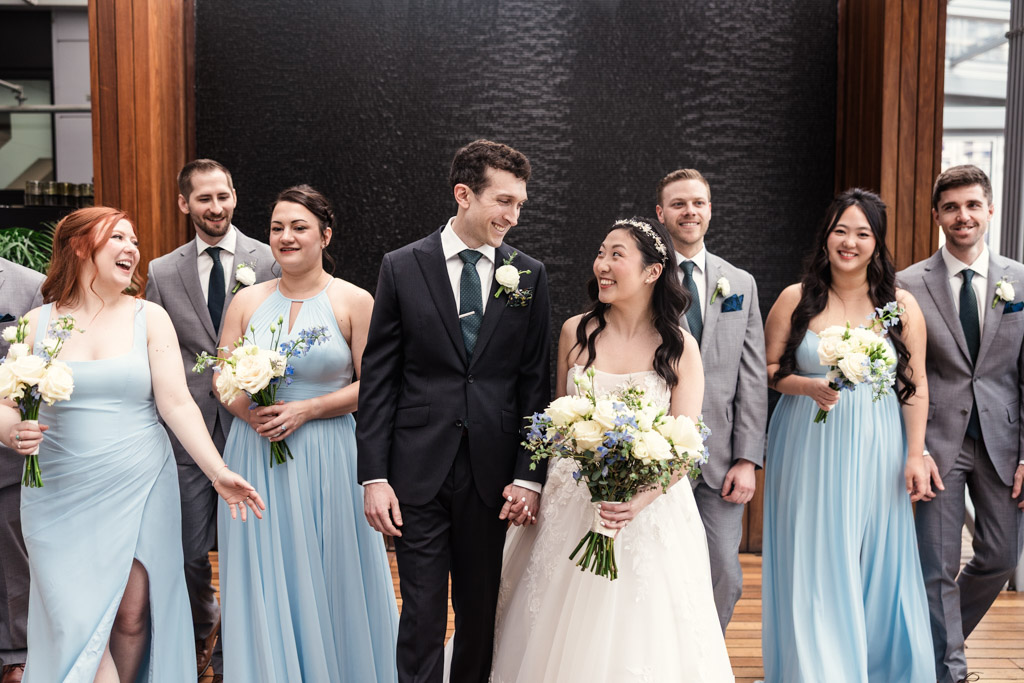 Bride and groom smile at each other at The Godfrey Hotel in downtown Chicago, surrounded by their wedding party