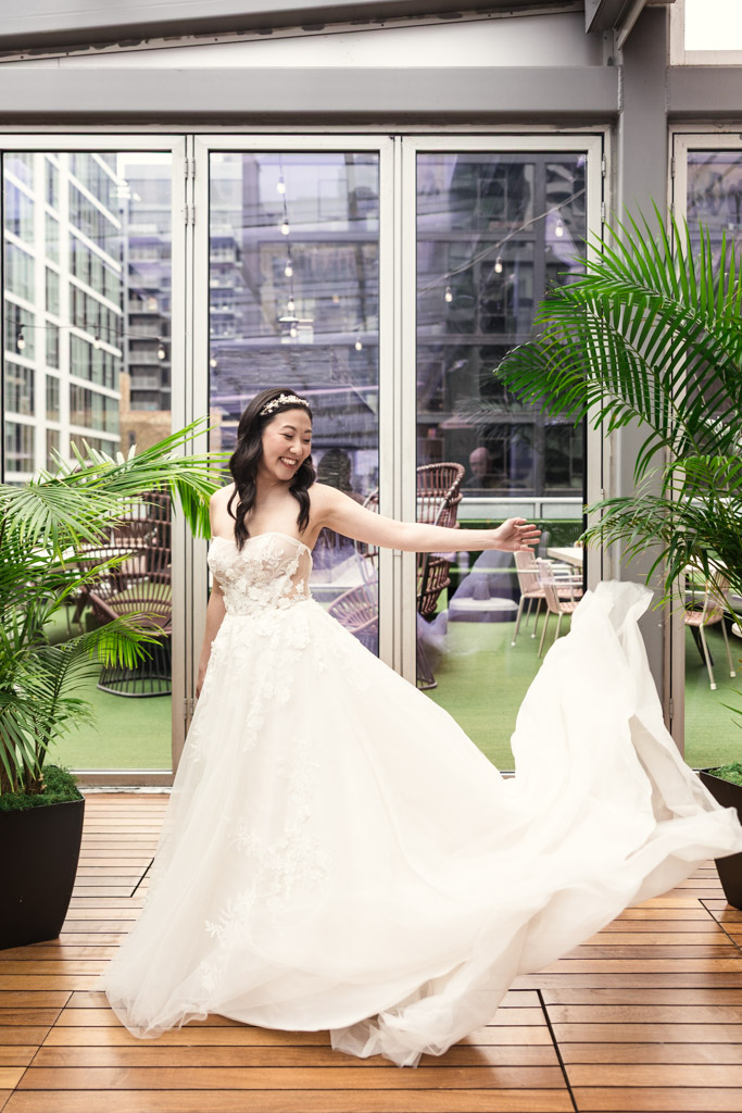 Bride in a white gown twirls on a wooden deck at The Godfrey Hotel in downtown Chicago