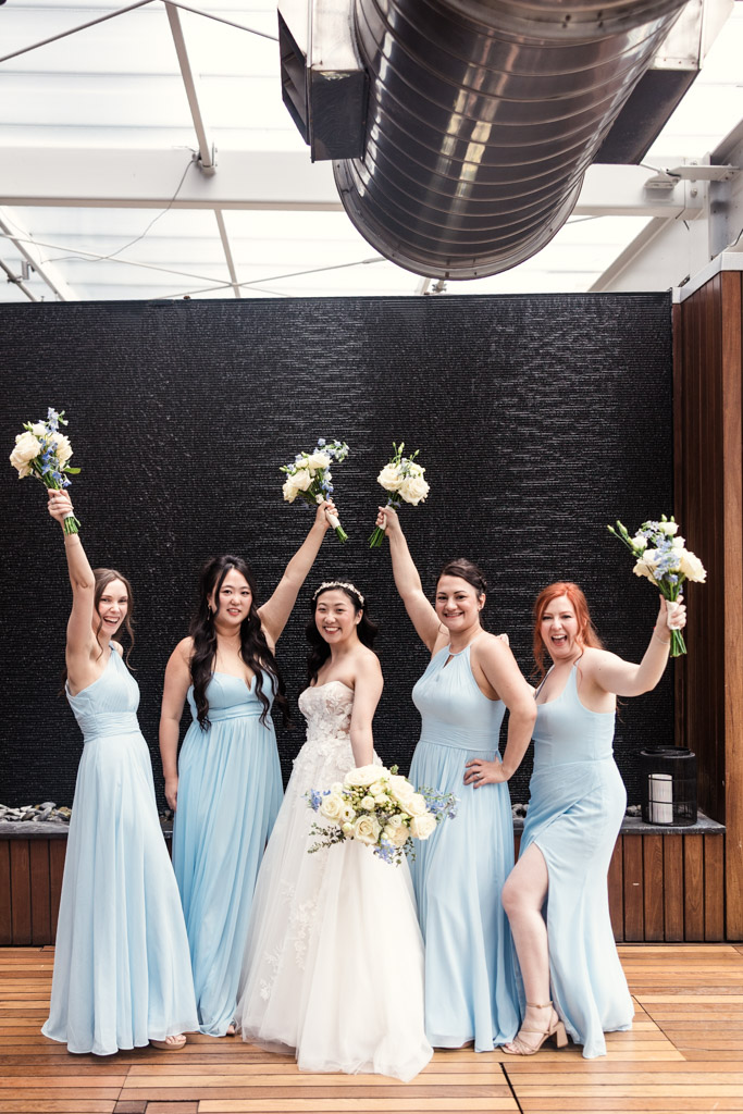 Bride and bridesmaids smile and hold bouquets up in celebration at Chicago Winery