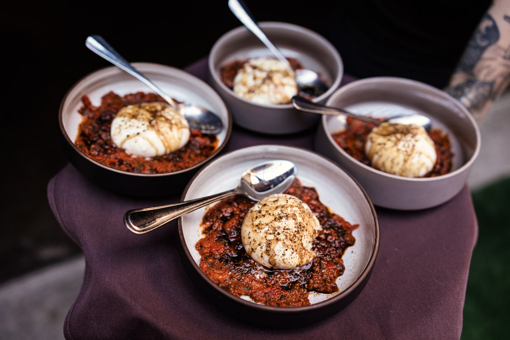 Four bowls of burrata cheese on a bed of tomato sauce, each with a spoon, served on a tray for Ada Street Chicago wedding reception