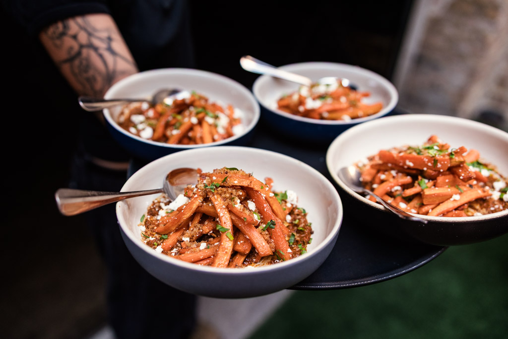 Four bowls of carrots are served on a black tray for wedding reception at Ada Street Chicago