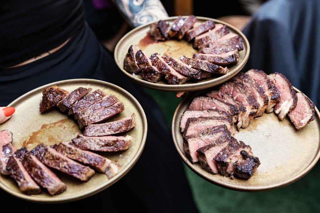 Three brown plates holding slices of grilled steak for wedding reception at Ada Street Chicago