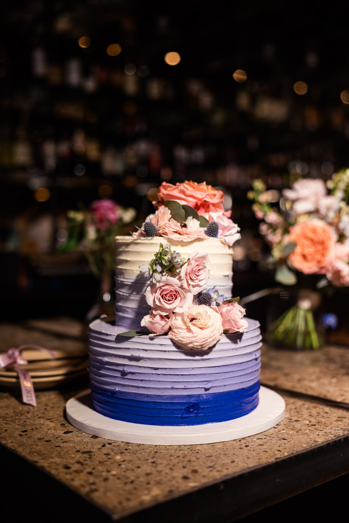 Two-tiered blue and purple ombre cake decorated with pink and peach flowers for wedding celebration at Ada Street Chicago