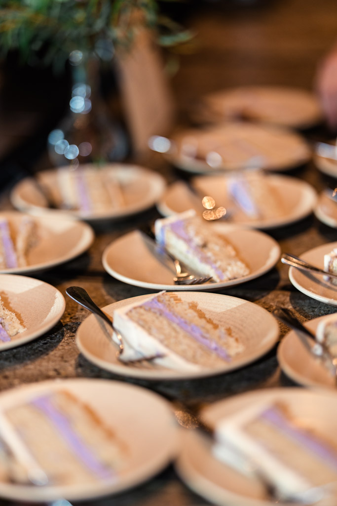 Slices of cake with purple frosting are arranged on plates with forks on a table for Ada Street Chicago wedding reception