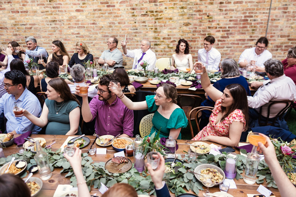 Guests at a long table raise glasses in a toast during Ada Street Chicago wedding reception