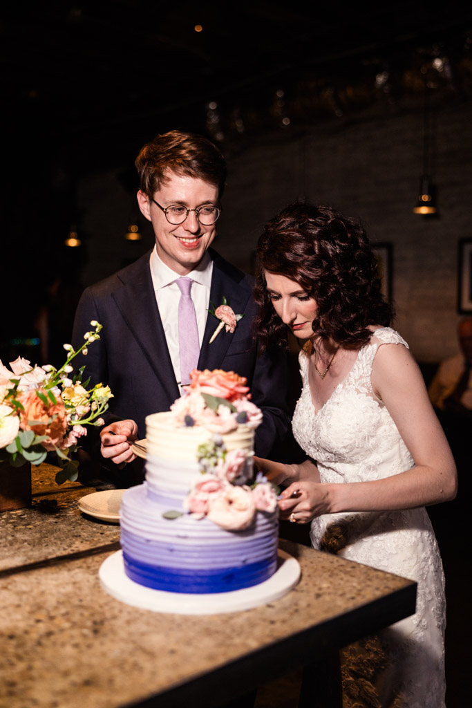 Bride and groom cut a tiered wedding cake decorated with flowers at their Ada Street Chicago wedding reception