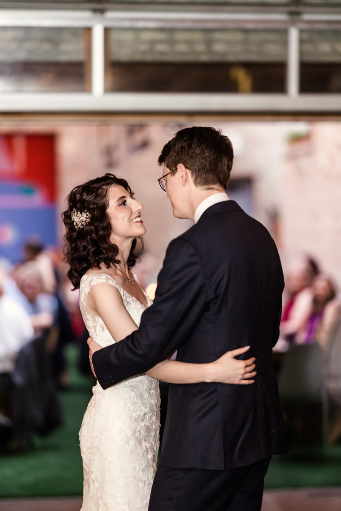 Bride and groom smile at each other during their first dance at their Ada Street Chicago wedding reception