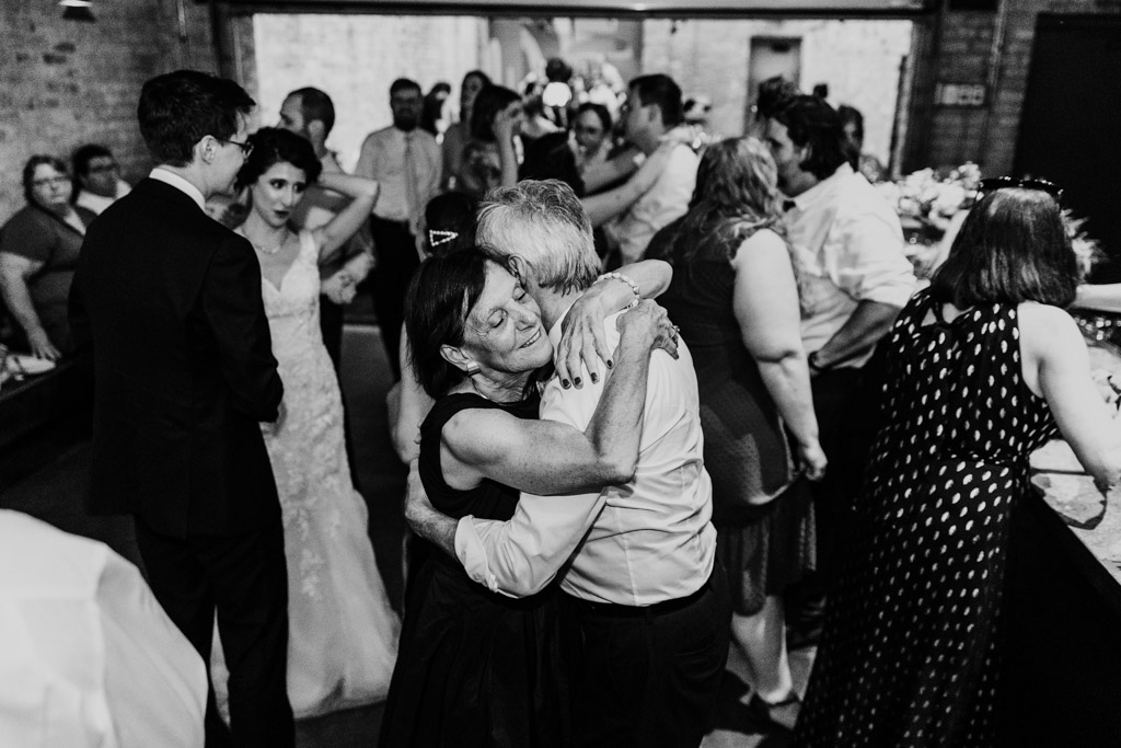 Black and white photo of couple hugging on a crowded dance floor during wedding reception at Ada Street Chicago
