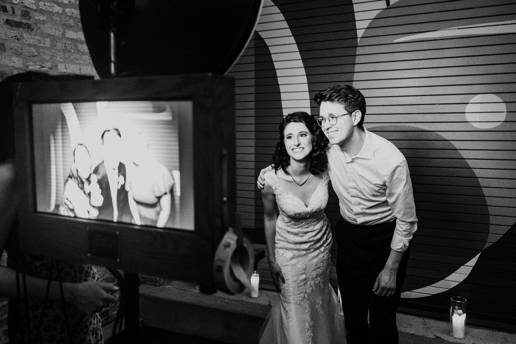Black and white photo of bride and groom smiling for a photo booth picture at their Ada Street Chicago wedding reception
