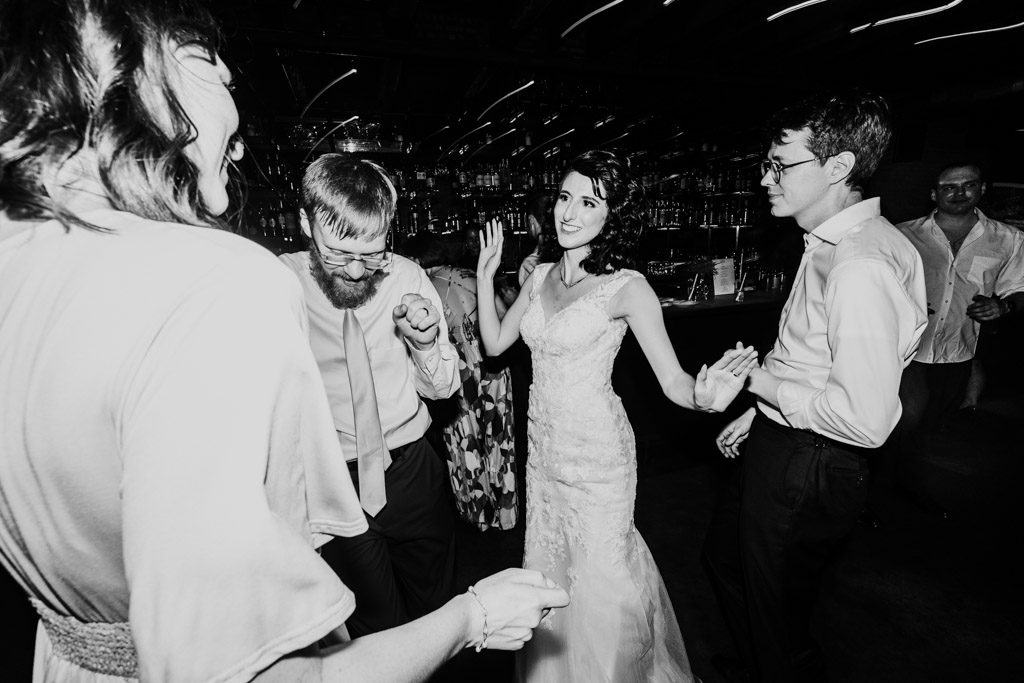 Black and white photo of bride and groom dancing with guests at their wedding reception at Ada Street Chicago
