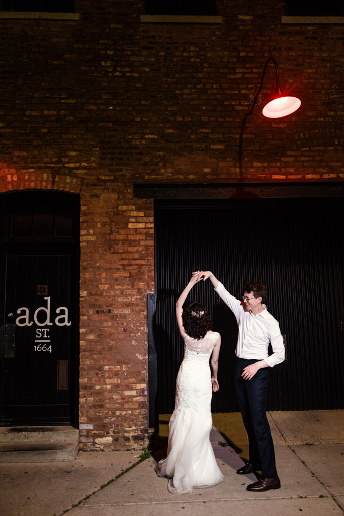 Newlyweds dance together at night under a red street light in front of Ada Street Chicago