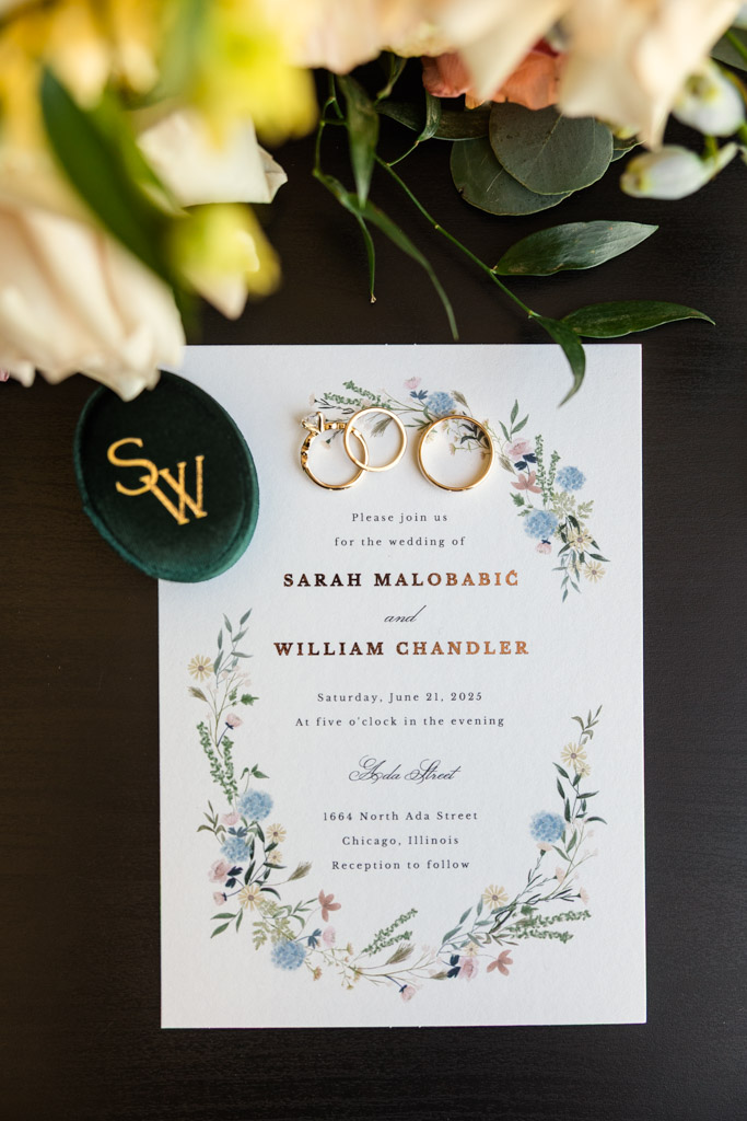 Wedding invitation with gold rings on top, surrounded by flowers for wedding at Ada Street Chicago