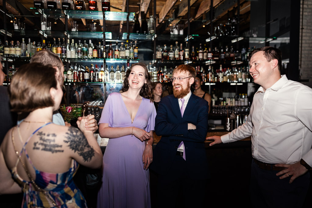 Guests laugh and chat together by the bar at Ada Street Chicago wedding reception