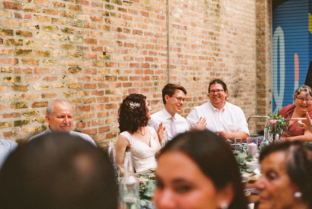 Film photo of newlyweds seated surrounded by guests during their Ada Street wedding reception