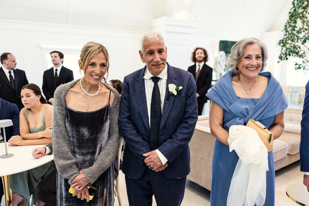 Bride's mother, groom's father and his wife watch bride and groom sign the ketubah during Être Farms wedding celebration