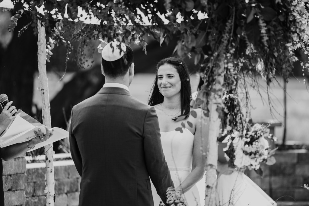 Black and white photo of bride and groom under the chuppah during their outdoor wedding ceremony at Être Farms