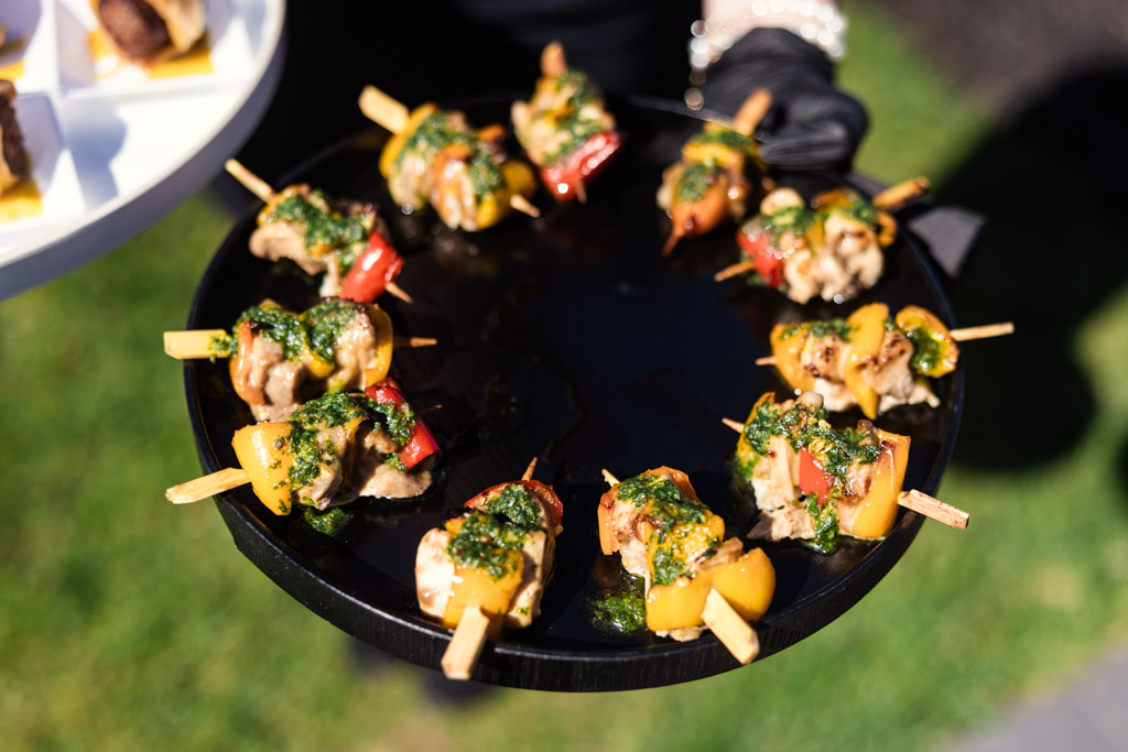 A black appetizer tray from Être Farms holds skewers of grilled meat and colorful vegetables, served with vibrant green sauce